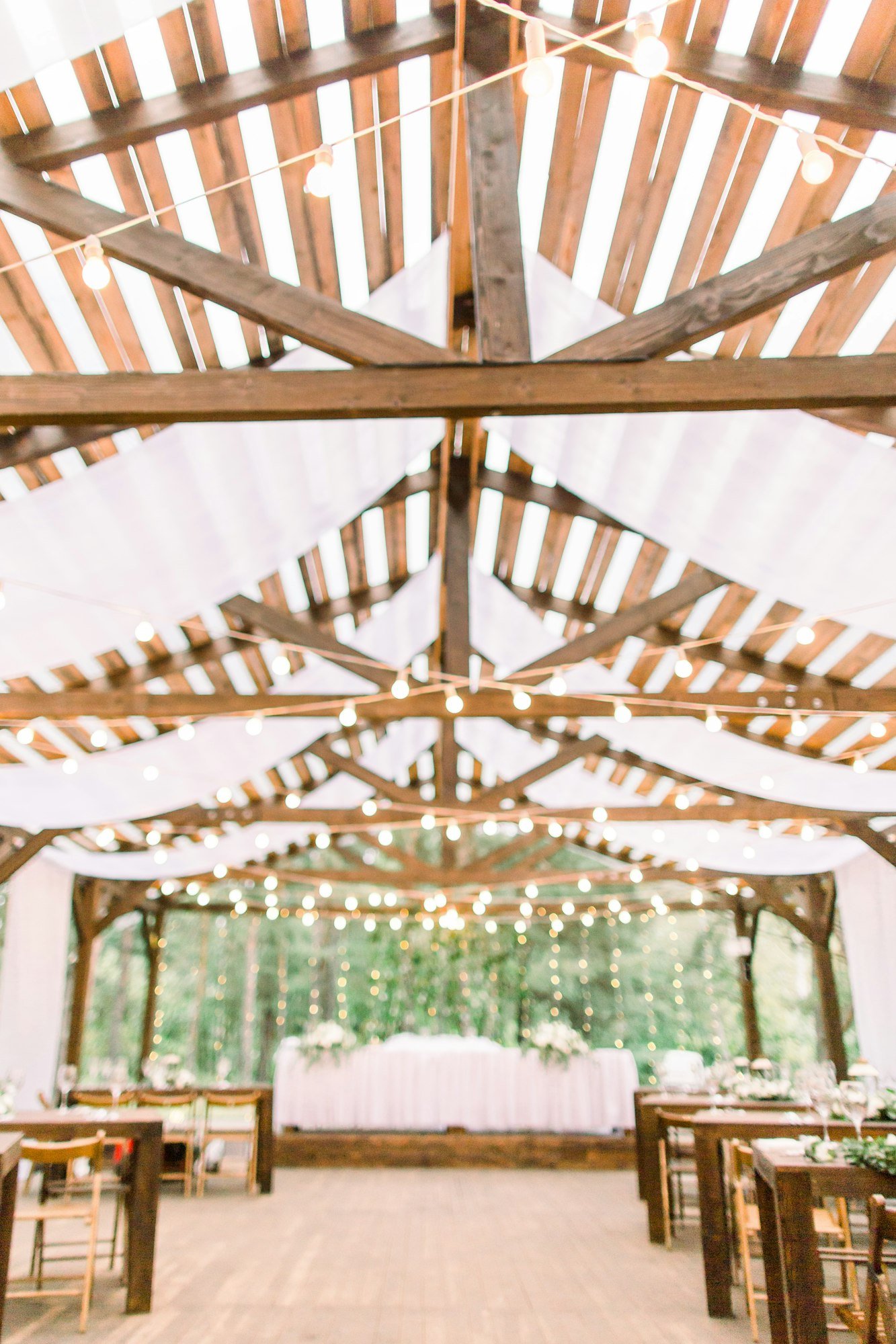 Interior of a wedding tables in rustic tent from wood, decorated with light bulbs, ready for guests